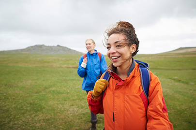 Woman smiling in backpack walking with friend in countryside