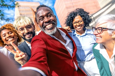 People of diverse age, race and gender smiling wide outside a building
